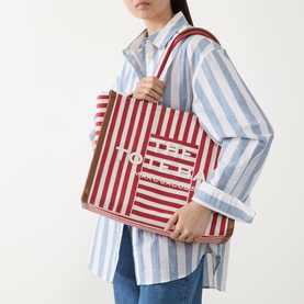 Model carrying Marc Jacobs The Stripe Canvas Large Tote Bag in True Red Multi, gold-tone hardware, logo lettering, leather trim, carry handles