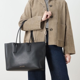 Model carrying Marc Jacobs The Pop J Marc Work Tote in black grained leather with gold-tone hardware, styled with a suede jacket and jeans