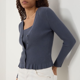 Model wearing Paige Pacific Blue ribbed cardigan with button-front detail, styled with white trousers.