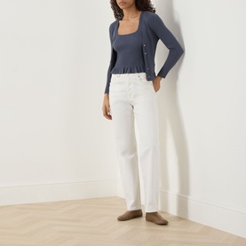 Model wearing Paige Pacific Blue cardigan with square neckline and button detail, styled with white wide-leg jeans and taupe loafers.