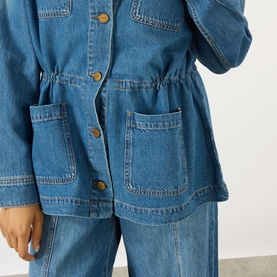 Model wearing Paige denim jacket in La Verne blue with gold-tone buttons, drawstring waist, and patch pockets, styled with matching wide-leg denim