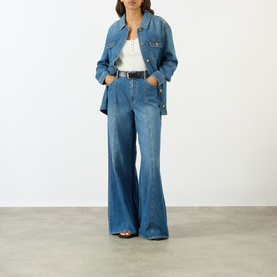 Model wearing Paige denim jacket in La Verne blue, styled with matching wide-leg jeans, white top and black belt.