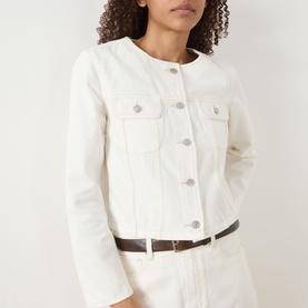 Model wearing Paige Toasted Ecru cotton jacket with silver buttons and chest pockets, styled with brown belt and white trousers.