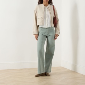 Model wearing Paige Vintage Biscotti cropped cotton jacket, styled with sage wide-leg jeans, white blouse and burgundy shoulder bag.