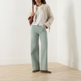 Model wearing Paige Vintage Biscotti cotton jacket with wide-leg sage trousers, white blouse and loafers, carrying brown bag.
