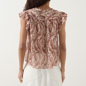 Model wearing Paige silk top in Antique White Multi with paisley print and flutter sleeves, styled with white wide-leg trousers