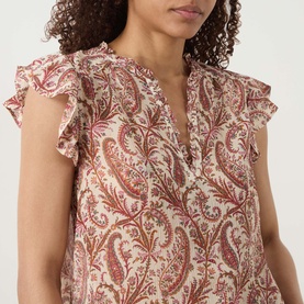 Model wearing Paige silk top in Antique White Multi with red paisley print, ruffle cap sleeves and V-neckline with lace trim detail