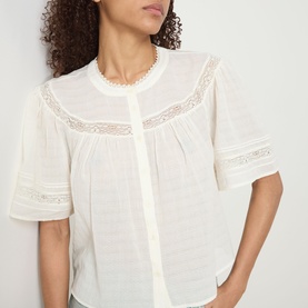 Model wearing Paige ivory cotton top with lace trim detailing, flutter sleeves, and button-front placket