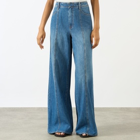 Model wearing Paige wide leg jeans in La Verne denim, high-rise waist, long flared leg, styled with dark strappy sandals.