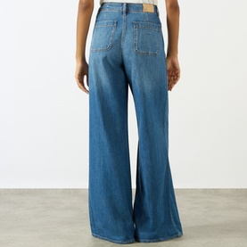 Model wearing Paige Wide Leg Jeans in La Verne, rear view showing high-rise waist, five-pocket styling and flared denim leg.