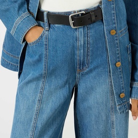 Model wearing Paige Wide Leg Jeans in La Verne blue denim with front seam detail, styled with a denim jacket and black belt.