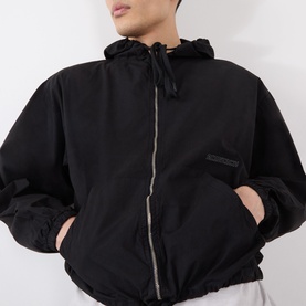 Model wearing Robyn Lynch black cotton casual jacket with hood, zip fastening, and hands in pockets
