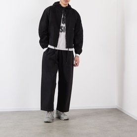 Model wearing Robyn Lynch black cotton casual jacket with matching wide-leg trousers, white graphic hoodie, and grey trainers.