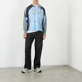 Model wearing Robyn Lynch Technical Denim Jeans in black, straight-leg with carpenter loop, styled with a blue graphic long-sleeve top and trainers.