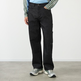 Model wearing Robyn Lynch Technical Denim Jeans in black; straight-leg, carpenter pocket, dark wash denim, styled with grey trainers and striped