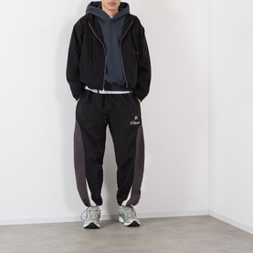 Model wearing Robyn Lynch slate blue hoodie, styled with black zip-up jacket, dark panelled joggers and grey trainers.