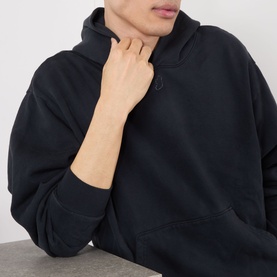 Model wearing Robyn Lynch Ireland Logo Embroidered Hoodie in slate blue, close-up showing tonal neck embroidery and kangaroo pocket.