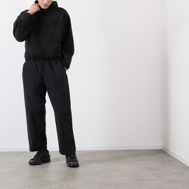 Model wearing Robyn Lynch black polyester sweatsuit with hoodie and wide-leg joggers, styled with black chunky trainers