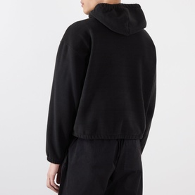 Model wearing Robyn Lynch black hooded sweatshirt, rear view, with matching black joggers. Cropped fit with elasticated hem and oversized sleeves.