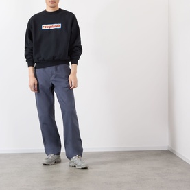Model wearing Robyn Lynch off black sweatshirt with logo print, styled with navy wide-leg trousers and grey trainers