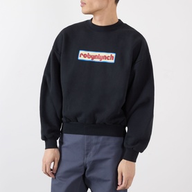Model wearing Robyn Lynch off black sweatshirt with logo box graphic print, styled with light grey trousers