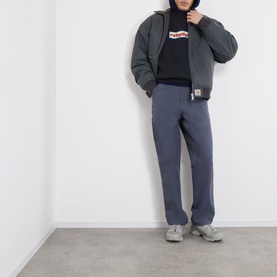 Model wearing Robyn Lynch Off Black sweatshirt with grey padded jacket, blue joggers and grey trainers.