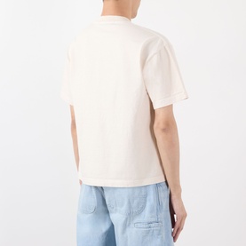 Model wearing Robyn Lynch Logo Graphic T-Shirt in off white, rear view, showing dropped shoulders and straight hem, styled with light blue jeans.