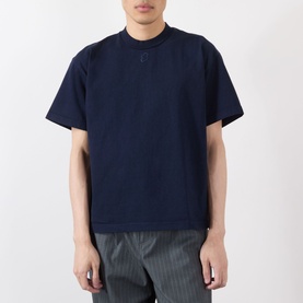 Model wearing Robyn Lynch navy cotton T-shirt with tonal logo embroidery at neckline, styled with grey striped trousers.