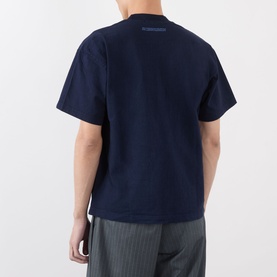 Model wearing Robyn Lynch navy cotton T-shirt, rear view, relaxed fit with dropped shoulders, styled with grey striped trousers.