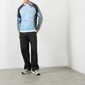Model wearing Robyn Lynch blue long-sleeve polyester T-shirt with graphic print and stripe sleeves, styled with black wide-leg trousers and grey