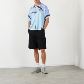Model wearing Robyn Lynch off black T-shirt with light blue graphic panel detail, styled with matching black shorts and grey trainers