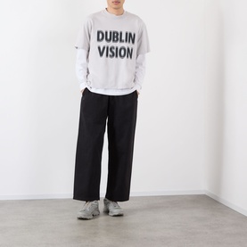 Model wearing Robyn Lynch grey Dublin Vision cotton T-shirt with black wide-leg trousers and grey trainers.