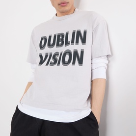 Model wearing Robyn Lynch grey cotton T-shirt with bold Dublin Vision graphic print, layered over long-sleeve white top.