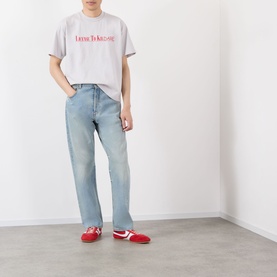 Model wearing Robyn Lynch grey cotton T-shirt with red text graphic, styled with light wash straight-leg jeans and red trainers.
