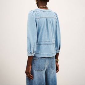 Model wearing Bash blue denim blouse with gathered yoke, three-quarter sleeves and pintuck details, styled with wide-leg jeans