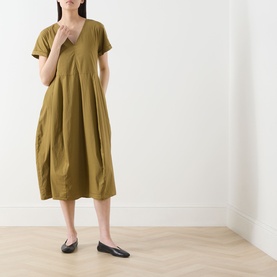 Model wearing Transit Pleated Pocket Dress in olive, V-neckline, short sleeves, midi length with pleated detail, styled with black flat shoes.