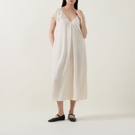 Model wearing Transit Textured Pocket Dress in sand, V-neckline, short sleeves, midi length, styled with black flat shoes