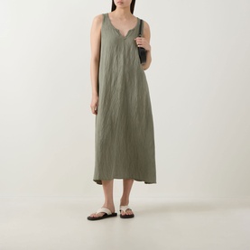 Model wearing Transit green sleeveless midi dress with V-neckline and relaxed fit, styled with white sandals and dark bag.