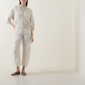 Model wearing Transit Zip Knit Cardigan in sand with V-neckline and three-quarter sleeves, styled with white tapered trousers and flat shoes.