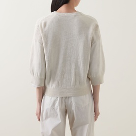 Model wearing Transit Zip Knit Cardigan in Sand, showing ribbed trims and three-quarter sleeves, styled with white wide-leg trousers.