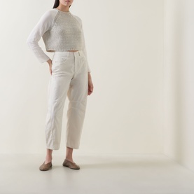 Model wearing Transit sand cotton-blend cropped knit jumper with white straight-leg trousers and grey flat mules