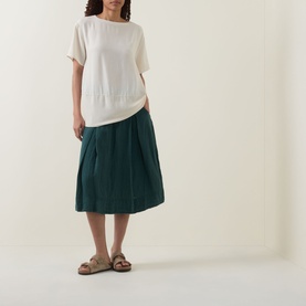 Model wearing Transit Textured Hybrid T-Shirt in Sand with round neckline, styled with teal midi skirt and tan sandals.