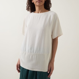 Model wearing Transit Textured Hybrid T-Shirt in sand with round neckline, short sleeves, contrast textured base, styled with green trousers.