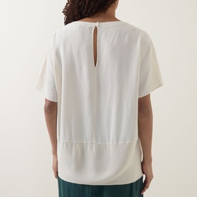 Model wearing Transit Textured Hybrid T-Shirt in sand, rear view showing keyhole back fastening, shadow stripe texture and contrast woven hem.