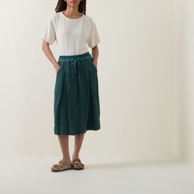 Model wearing Transit Textured Hybrid T-Shirt in Sand with round neckline, styled with teal midi skirt and tan sandals.