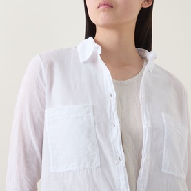 Model wearing Transit Patch Pocket Shirt in white, showing pointed collar, button fastening and chest patch pocket, styled over a cream slip.
