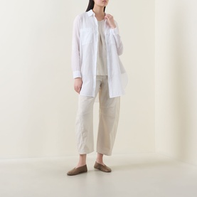 Model wearing Transit Patch Pocket Shirt in white with pointed collar and curved hem, styled with beige cropped trousers and flat mules.