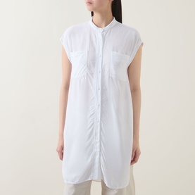 Model wearing Transit Patch Pocket Blouse in white, longline with cap sleeves, standing collar, chest patch pockets, styled with cream trousers