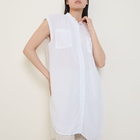 Model wearing Transit Patch Pocket Blouse in white, sleeveless longline cotton shirt with standing collar and chest patch pocket.