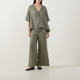 Model wearing Transit green V-neck short-sleeve linen-blend shirt, styled with matching wide-leg trousers and black flat shoes.